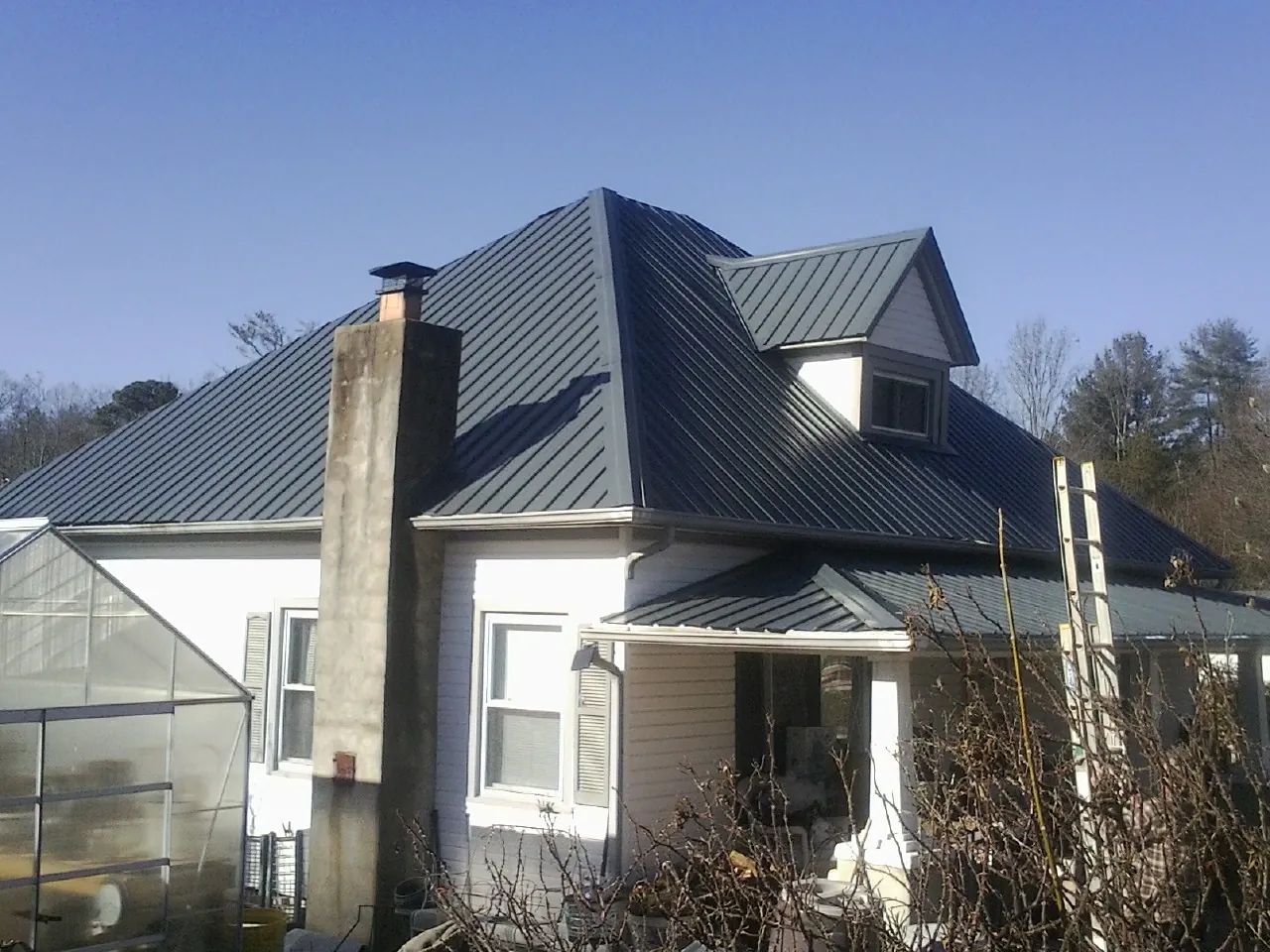 Dark blue standing seam metal roof on a white farmhouse with dormer — Slate & Tile Roof Repair by Roofing Brothers in Sebastopol