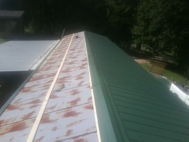 Old rusted panels beside newly installed green metal roofing — Wind Damage Roof Repair by Roofing Brothers in Sebastopol