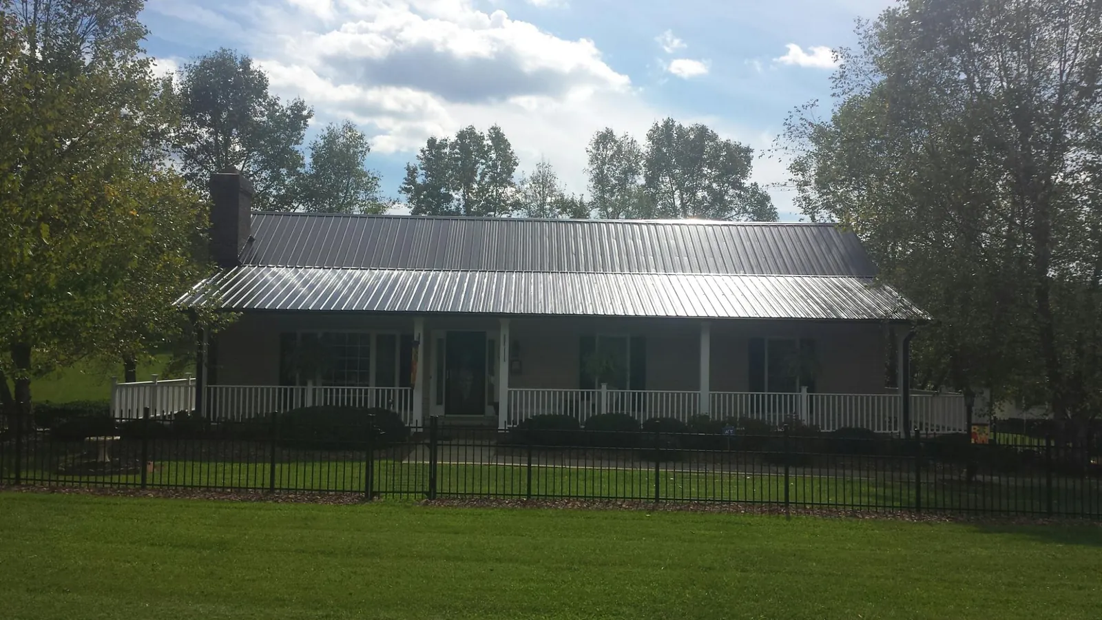 Gray metal roof on a brick ranch with a full width front porch — Gutter Guard Installation work by our crew in Sebastopol