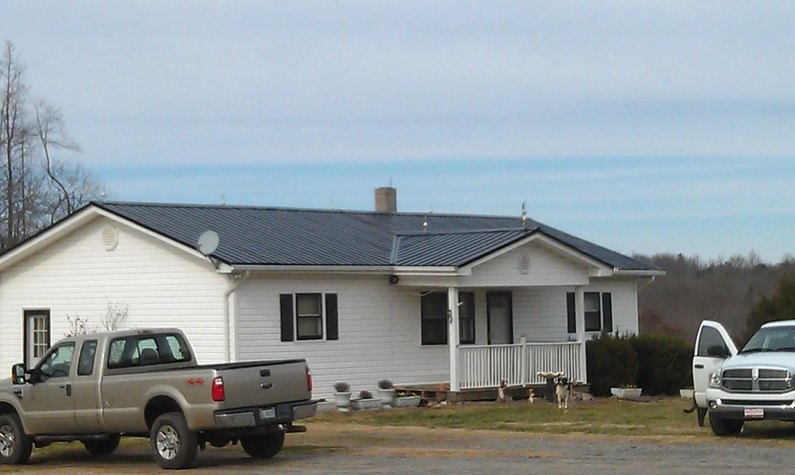 Finished dark metal roof on a white ranch home with work trucks parked in Sebastopol