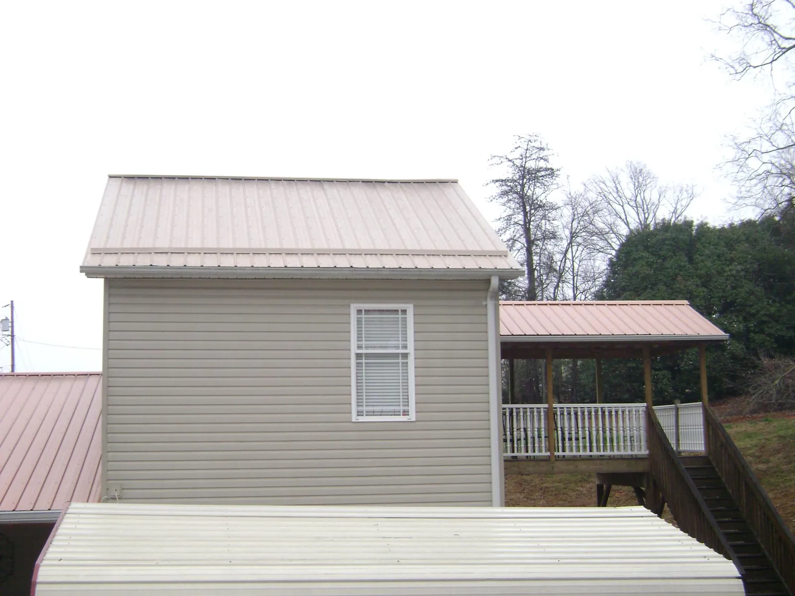 Tan metal roofs on a two story addition and attached porch, from a Roof Replacement job in Sebastopol