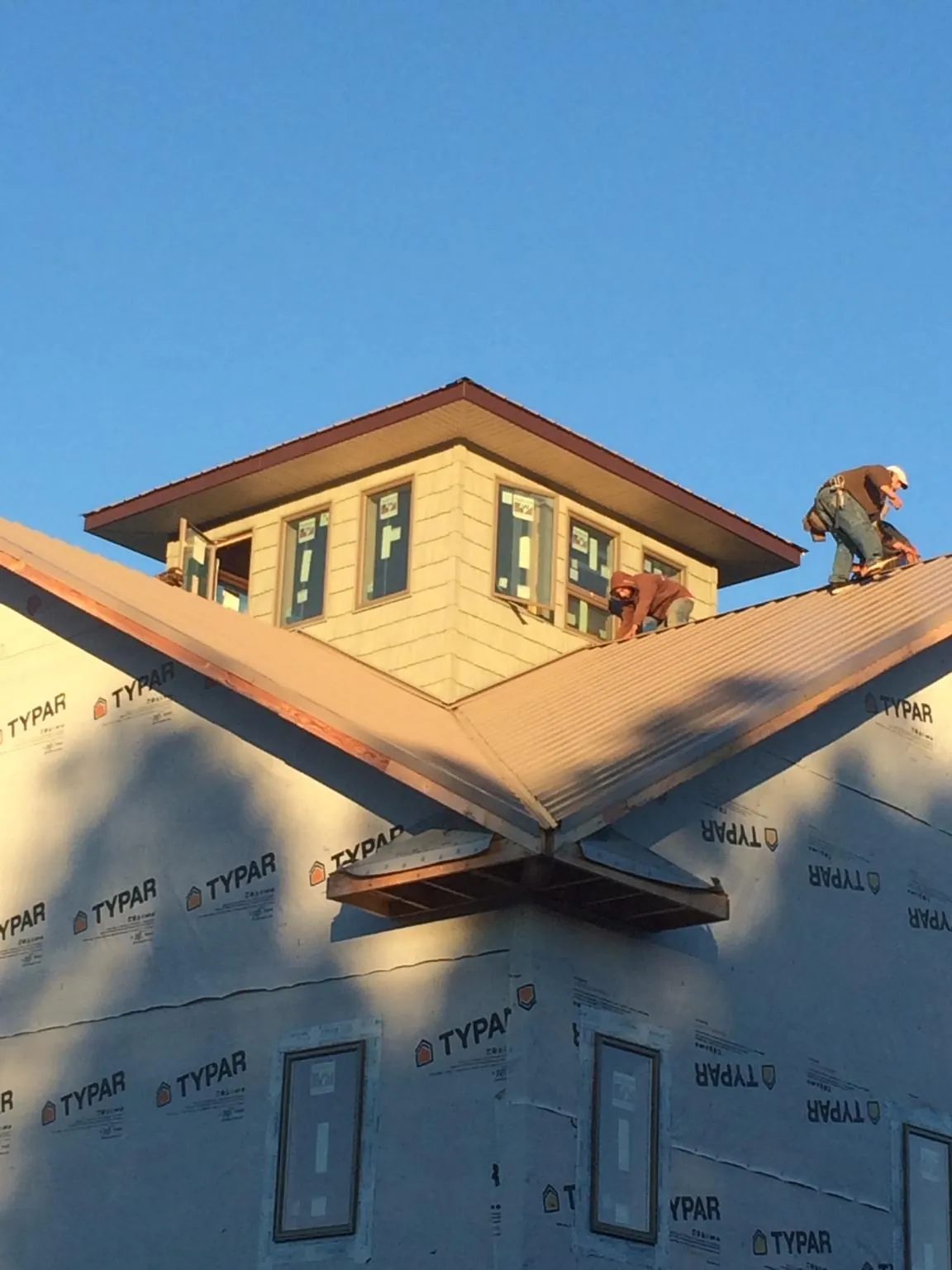 Roofers working around a rooftop cupola on a new metal roof at sunset — Roof Waterproofing in Sebastopol by Roofing Brothers